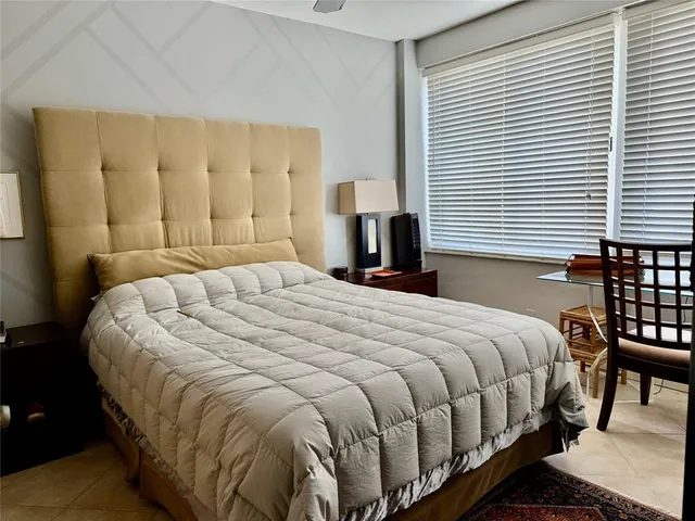 a large bed sitting in a bedroom next to a window and lamp