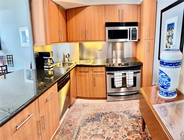a kitchen with stainless steel appliances granite countertop a stove and a wooden cabinets