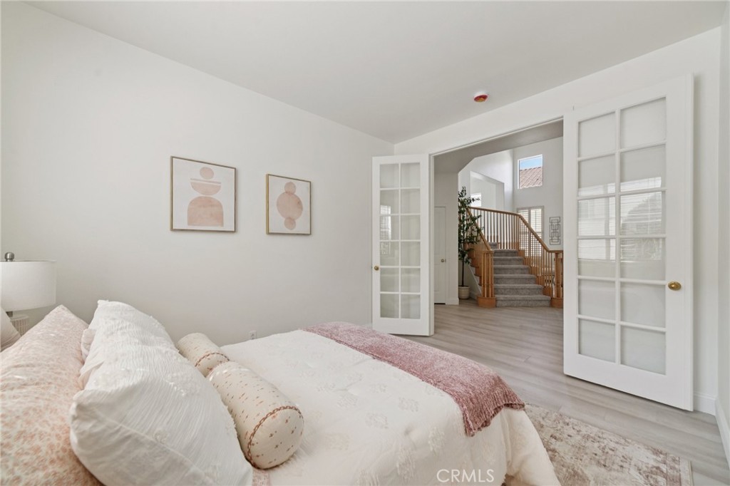 12440 Butler Way Tustin, CA 92782 - Photo 17 of 65 First level bedroom with double French style doors. Taking a right after leaving the room will take you to a full bathroom on the right. laundry room on the left with the entrance to the garage straight ahead.