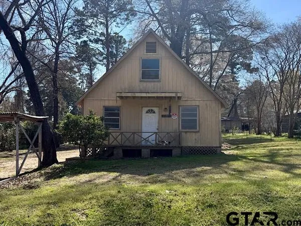 a view of a house with a yard and a large tree