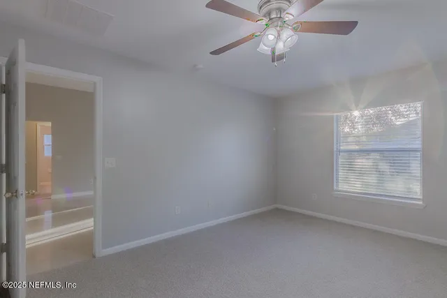 an empty room with windows and fan