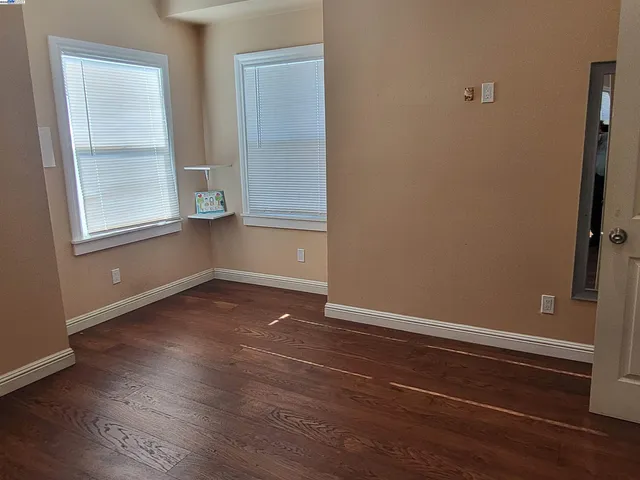 an empty room with wooden floor and windows