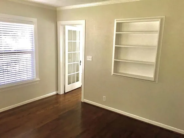 a view of an empty room with a window and wooden floor