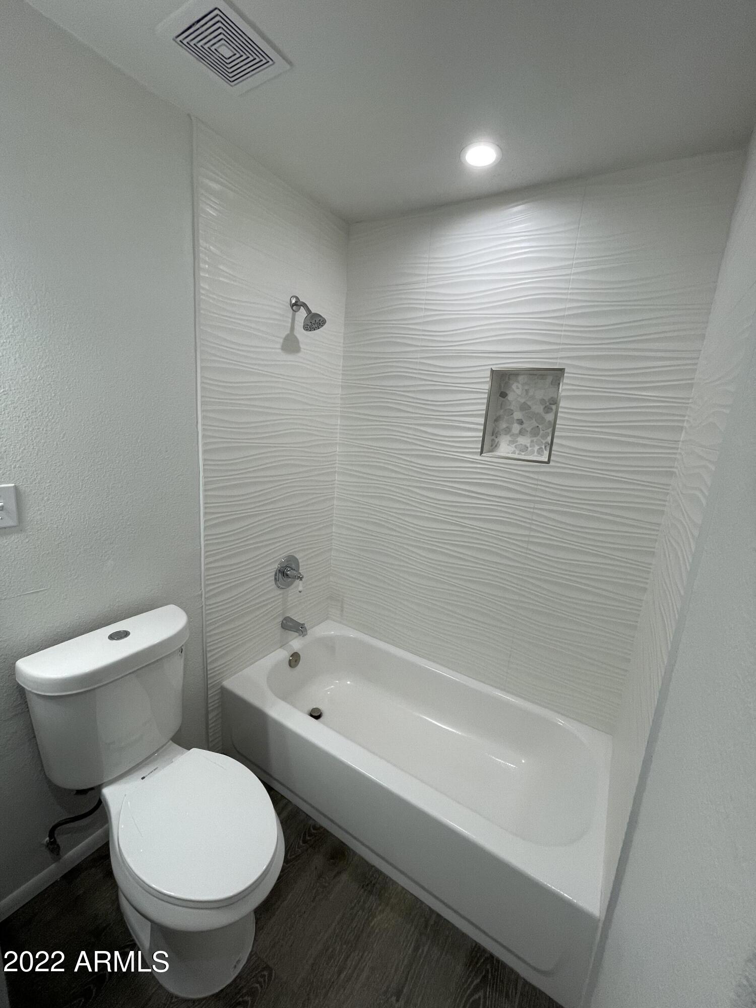 5207 West Osborn Road Phoenix, AZ 85031 - Photo 25 of 35 a white toilet sitting next to a bath tub
