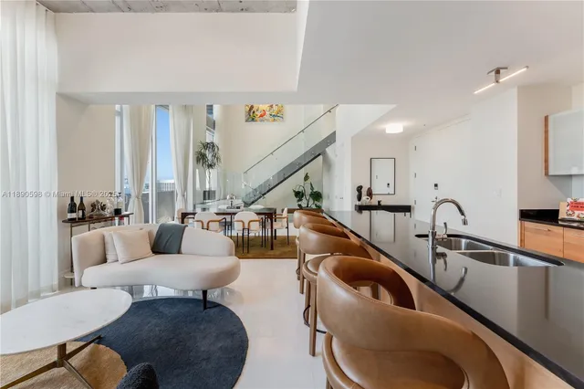 a living room with furniture kitchen view and a large window
