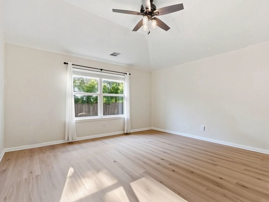 1201 Ridgewood Drive Leander, TX 78641 - Photo 14 of 28 Empty room featuring ceiling fan, light wood-style floors, and vaulted ceiling