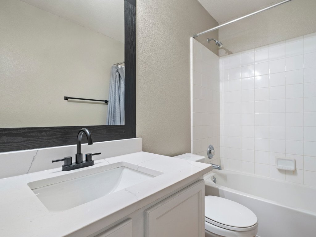 1201 Ridgewood Drive Leander, TX 78641 - Photo 23 of 28 Full bathroom featuring a textured wall, vanity, and shower / bathtub combination with curtain