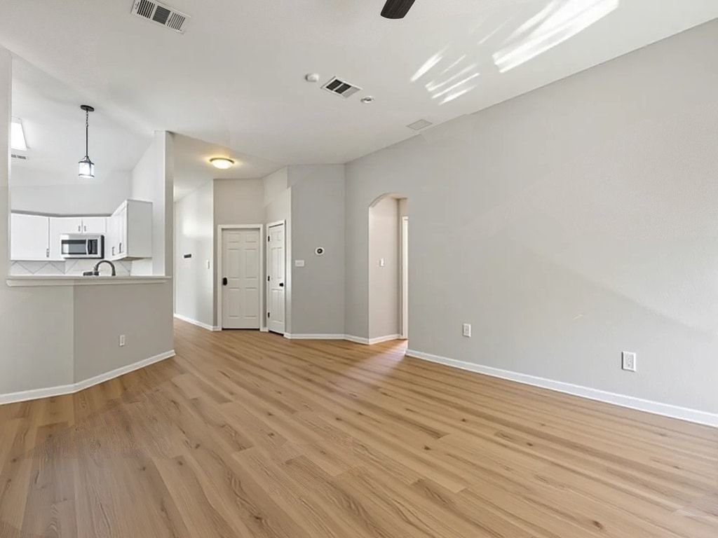 1201 Ridgewood Drive Leander, TX 78641 - Photo 4 of 28 Unfurnished living room with arched walkways, a ceiling fan, light wood-type flooring, and lofted ceiling