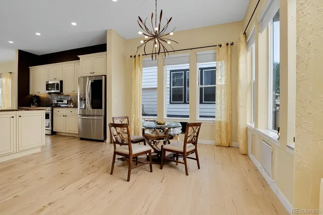 a kitchen with stainless steel appliances a dining table chairs and refrigerator