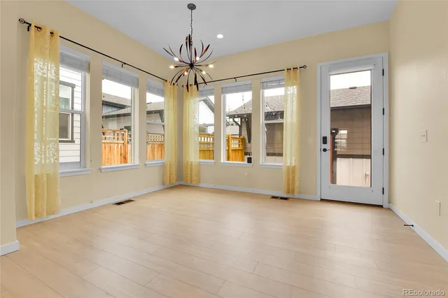 a view of an empty room with window and chandelier fan