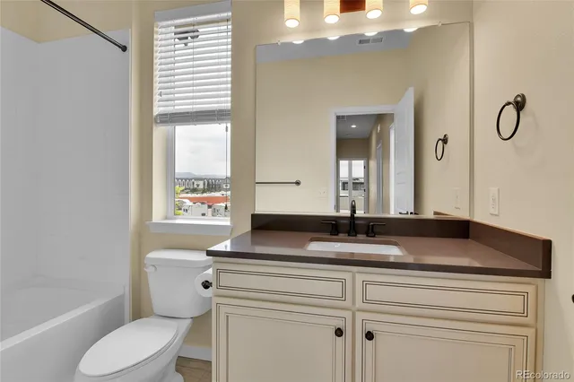a bathroom with a granite countertop sink toilet and mirror