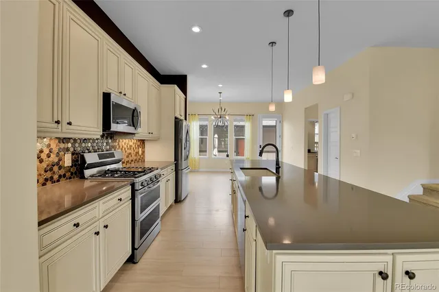 a kitchen with stainless steel appliances granite countertop a sink a stove and a refrigerator