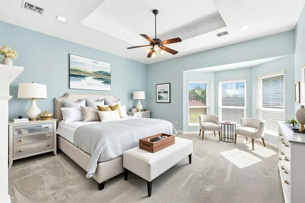 a bedroom with a bed couch chandelier and a window