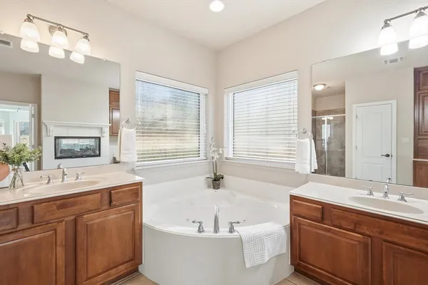 a bathroom with a bathtub a double vanity sink and mirror