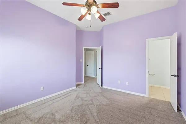 a view of an empty room with chandelier fan