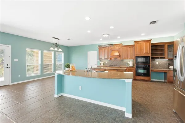 a room with stainless steel appliances kitchen island granite countertop a refrigerator and cabinets