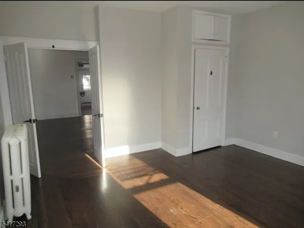an empty room with wooden floor and a hallway