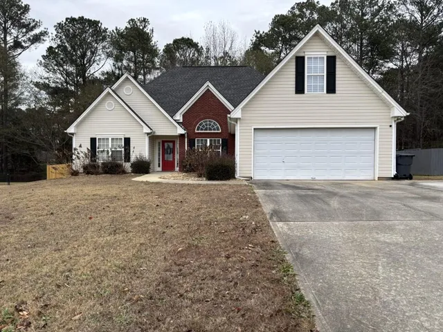 a view of a yard in front of a house with large windows