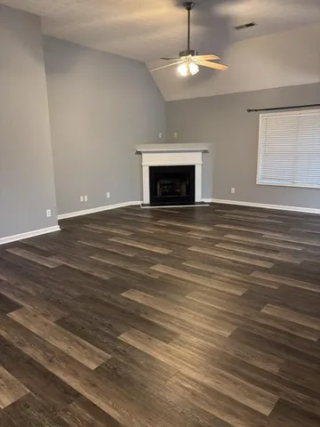 an empty room with wooden floor fireplace and chandelier