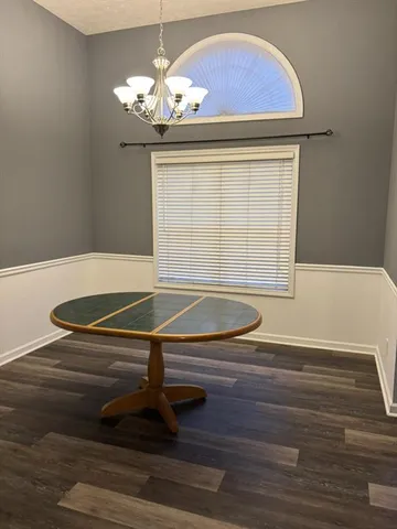 a room with wooden floor pool table and chandelier