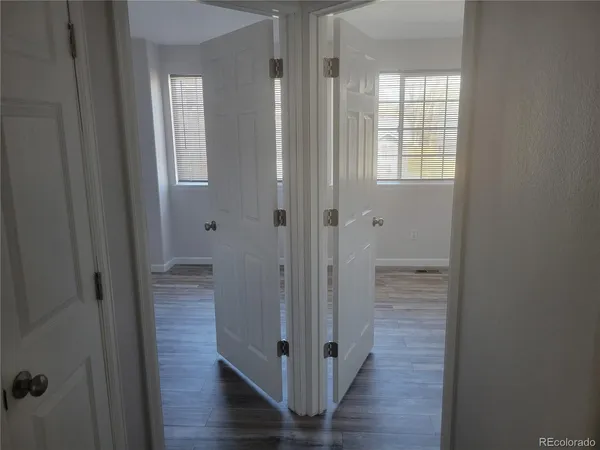 a view of a hallway with wooden floor and closet area