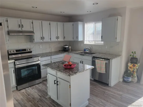 a kitchen with white cabinets and appliances
