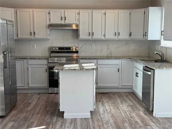 a kitchen with a stove top oven and white cabinets
