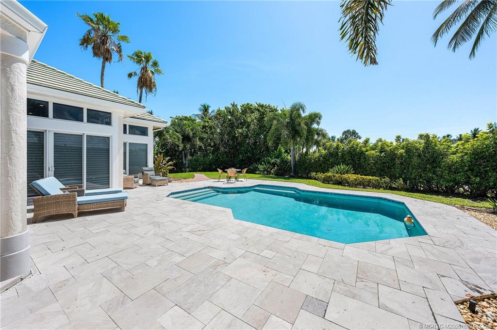 7000 Southeast Lakeview Terrace Stuart, FL 34996 - Photo 36 of 56 a view of swimming pool with lounge chair and dinning table under an umbrella