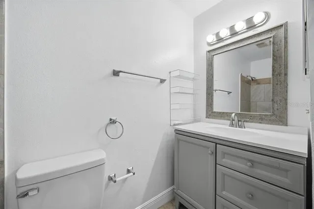 a bathroom with a granite countertop sink toilet and mirror