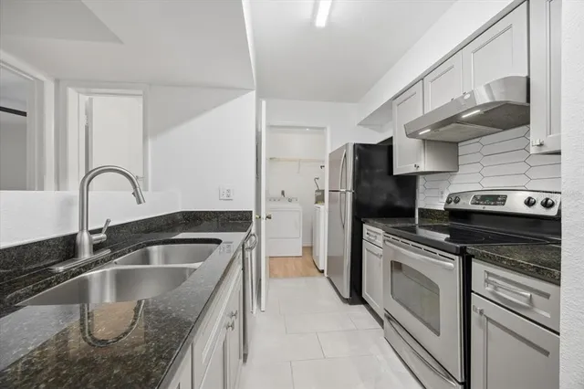 a kitchen with granite countertop a sink stainless steel appliances and cabinets