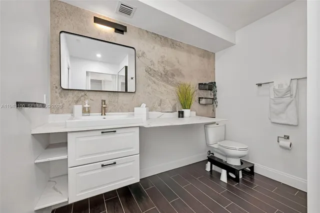 a bathroom with a toilet a sink a mirror and vanity