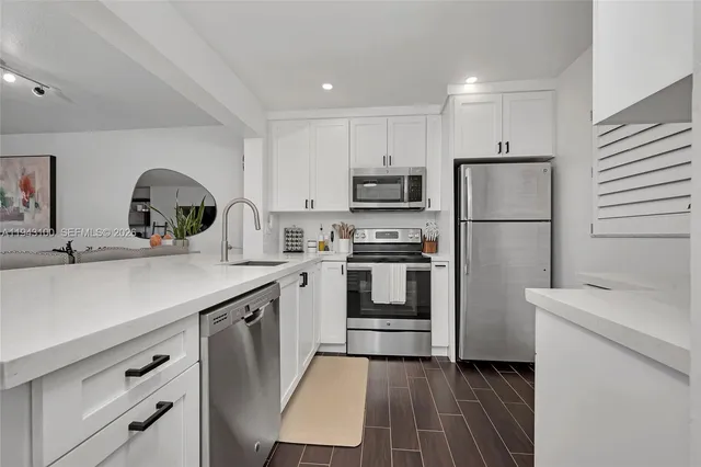 a kitchen with refrigerator a sink and white cabinets