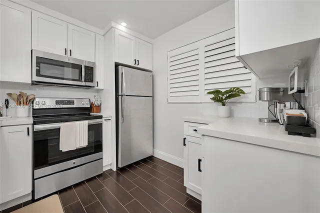 a kitchen with white cabinets stainless steel appliances and a window