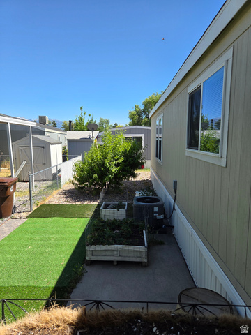 1275 Thrush Road Salt Lake City, UT 84123 - Photo 2 of 20 Side yard featuring artificial turf, raised garden beds, and a peach tree
