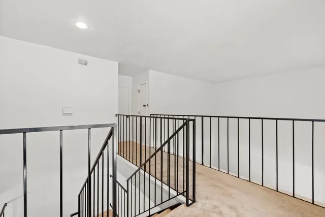 a view of staircase with railing and white walls