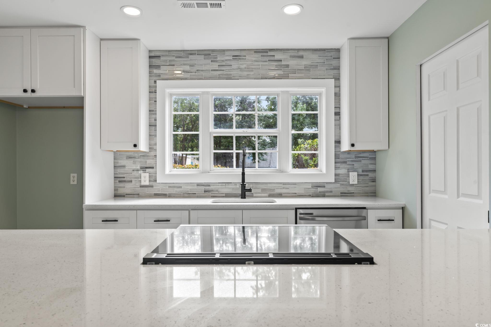 540 Boundary Avenue Murrells Inlet, SC 29576 - Photo 25 of 40 Kitchen with backsplash, white cabinetry, light st
