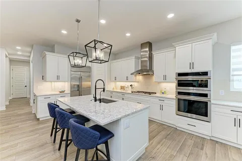 a kitchen with stainless steel appliances granite countertop a kitchen island hardwood floor sink stove dining table and chairs