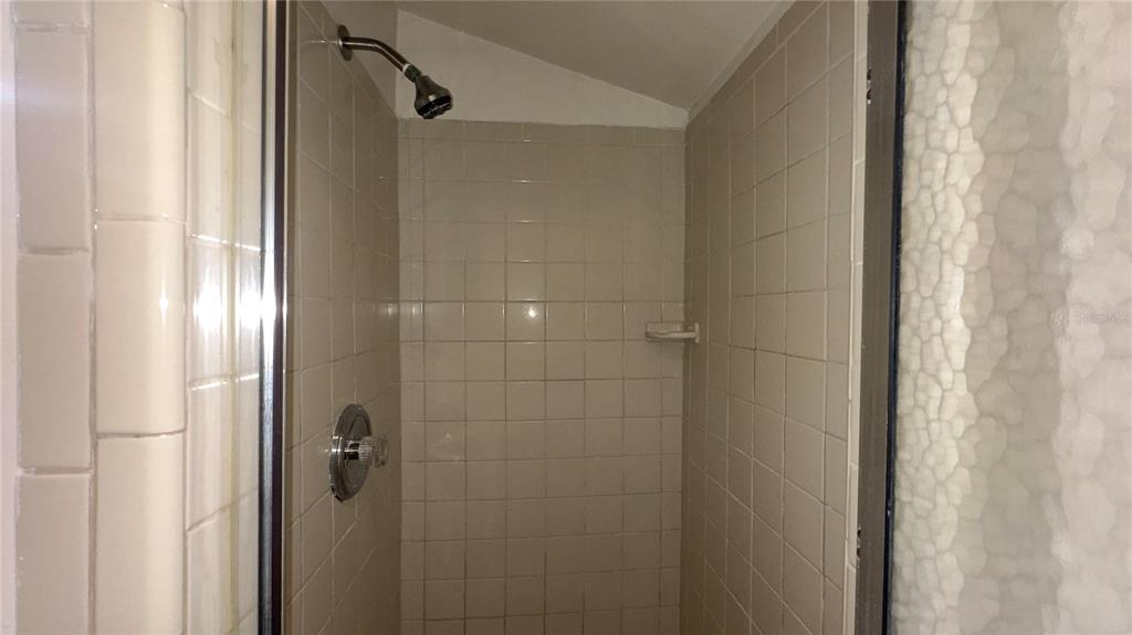 616 Massachusetts Avenue, Unit A St. Cloud, FL 34769 - Photo 13 of 15 a bathroom with a glass shower door