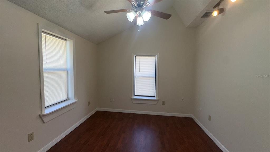 616 Massachusetts Avenue, Unit A St. Cloud, FL 34769 - Photo 5 of 15 an empty room with wooden floor windows and fan