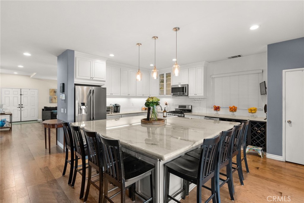 29602 Cool Meadow Drive Menifee, CA 92584 - Photo 3 of 31 a kitchen with stainless steel appliances kitchen island granite countertop a dining table chairs and white cabinets
