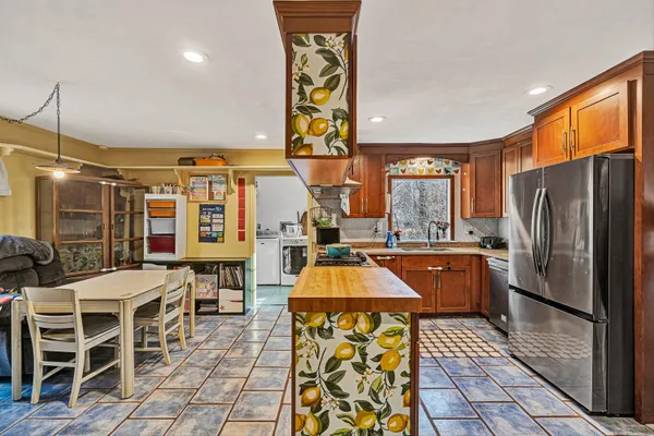 a kitchen with stainless steel appliances granite countertop a refrigerator a sink a stove and chairs