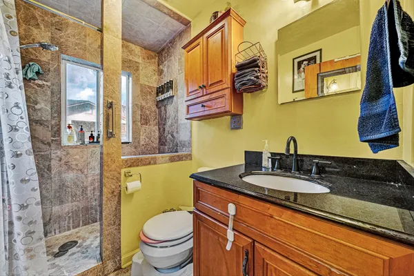 a bathroom with a granite countertop toilet sink and mirror