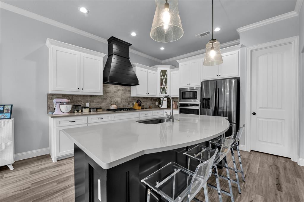 305 Familia Court Azle, TX 76020 - Photo 11 of 40 a kitchen with stainless steel appliances kitchen island granite countertop a stove a refrigerator a sink a dining table and chairs with wooden floor