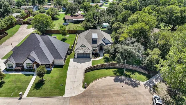 an aerial view of a house with swimming pool and large trees