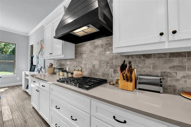 a kitchen with stainless steel appliances white cabinets and a stove top oven