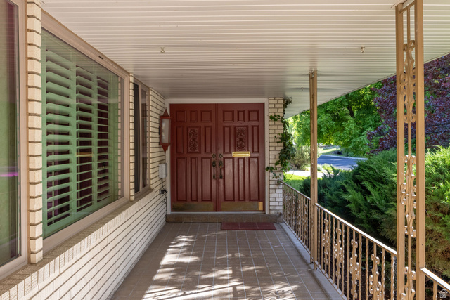 1365 Sumac Drive Logan, UT 84321 - Photo 65 of 66 Covered front porch featuring a brick facade, decorative iron railings, and a tiled floor