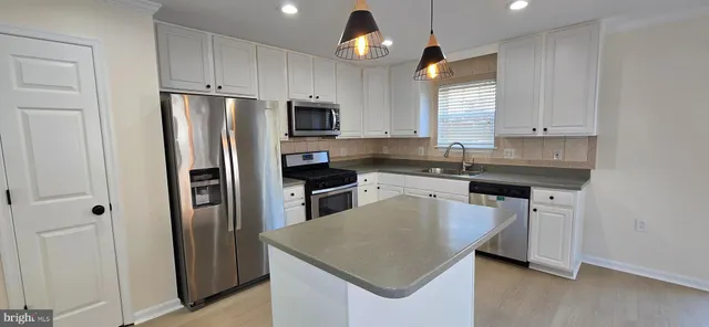 a kitchen with stainless steel appliances a refrigerator a sink a stove a microwave and island