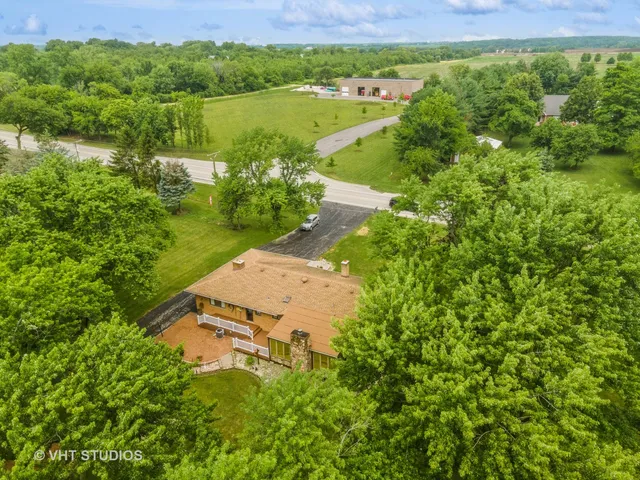 an aerial view of residential house with outdoor space and trees all around