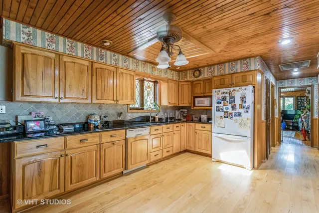 a large kitchen with stainless steel appliances granite countertop a refrigerator and cabinets