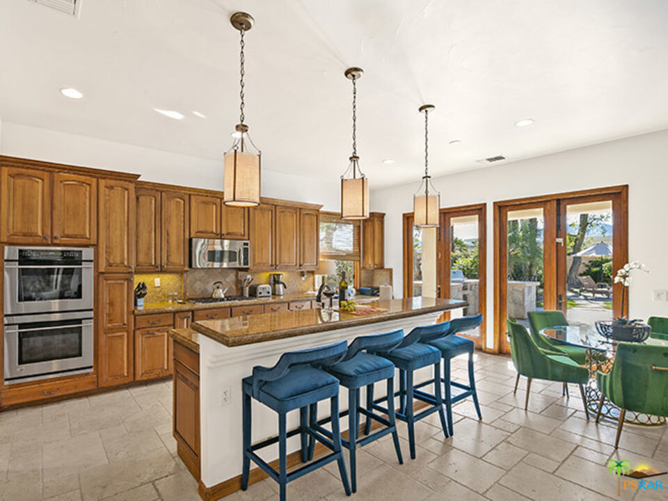 72733 Verbenia Road Rancho Mirage, CA 92270 - Photo 5 of 33 a kitchen with stainless steel appliances a dining table chairs and granite counter tops